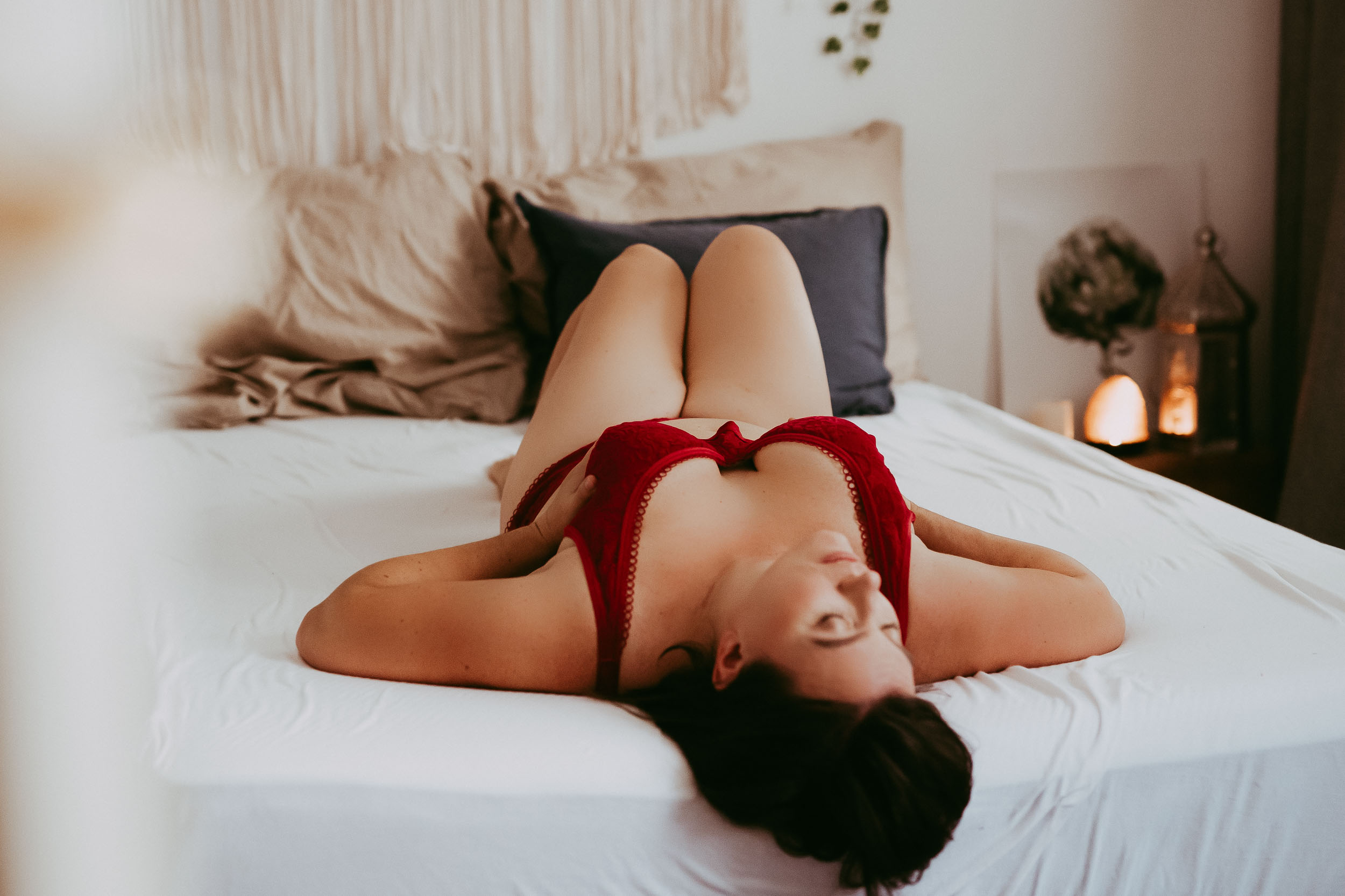 Astrid in roter Unterwäsche auf dem Bett, am Rücken liegend